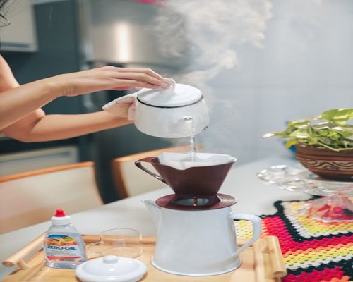 A person pouring hot water over natural cacao paste in a kitchen setting